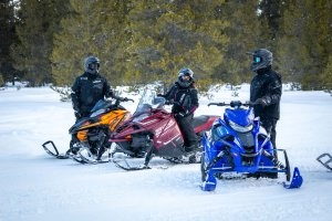 Riders talking around their snowmobiles in the snow